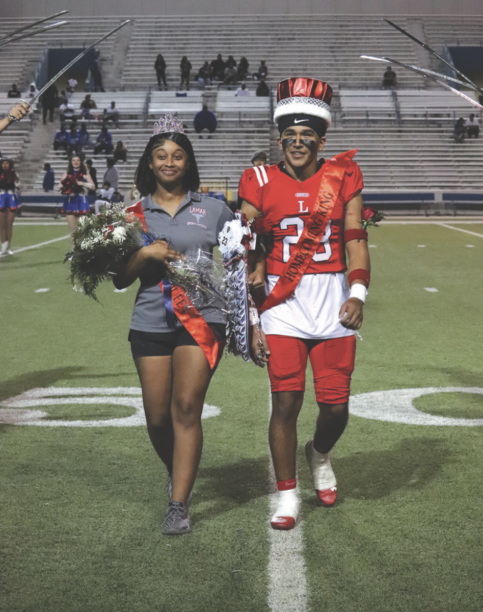 After being crowned homecomiang king and queen, Andrenai Turbin
(left) and Pedro Carreon (right) lock elbows and smile to the crowd.